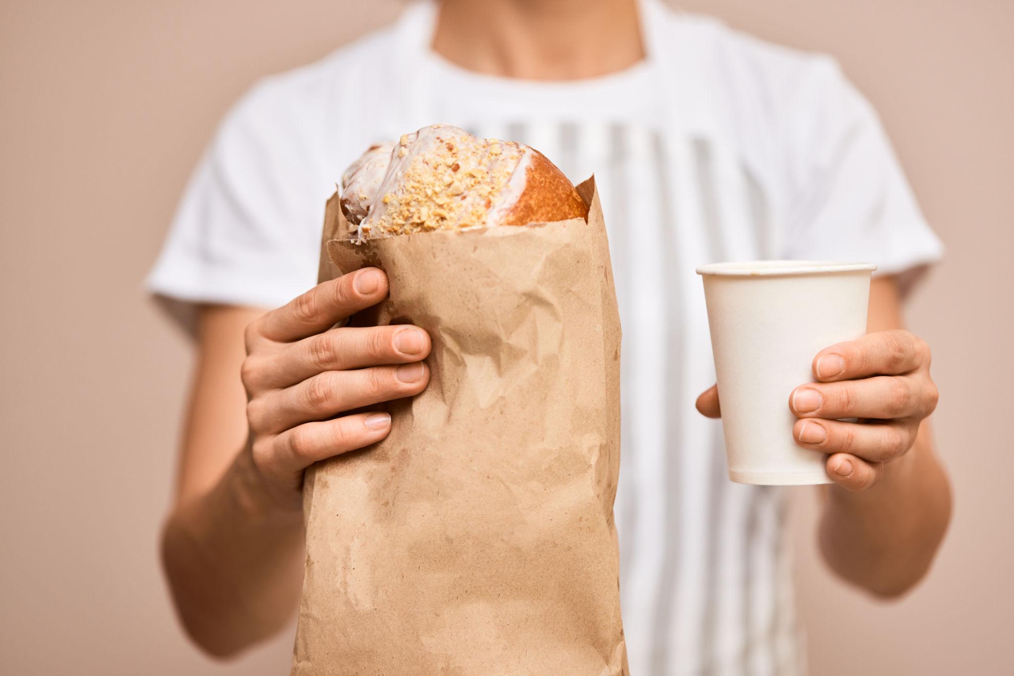 В кофейне гостю подают кофе и круассан в белой жиростойкой бумаге